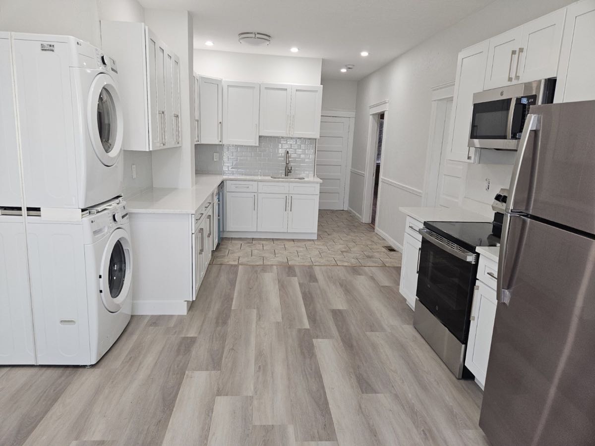 Renovated white kitchen with stainless-steel appliances and in-unit laundry at 30 Thorne Street, Apartment 1